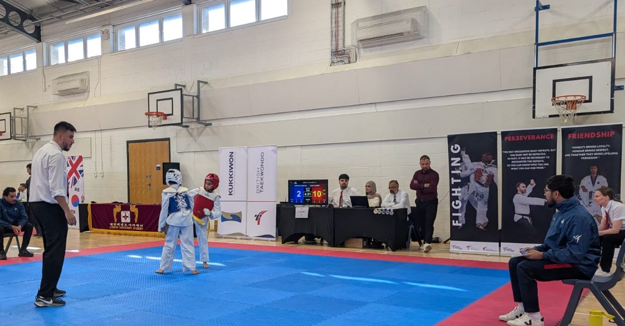 A coach sits at the side of court 2 while two young fighters compete